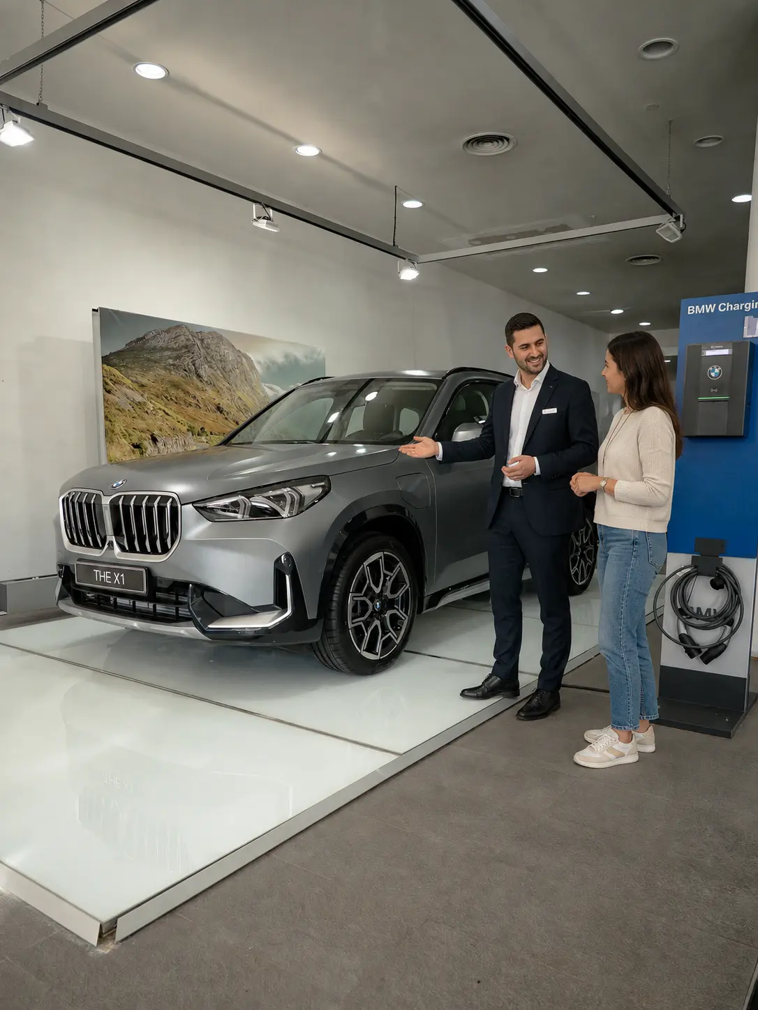 Asesor de Rhein Motor conversando con una persona junto a un BMW X1 en el concesionario