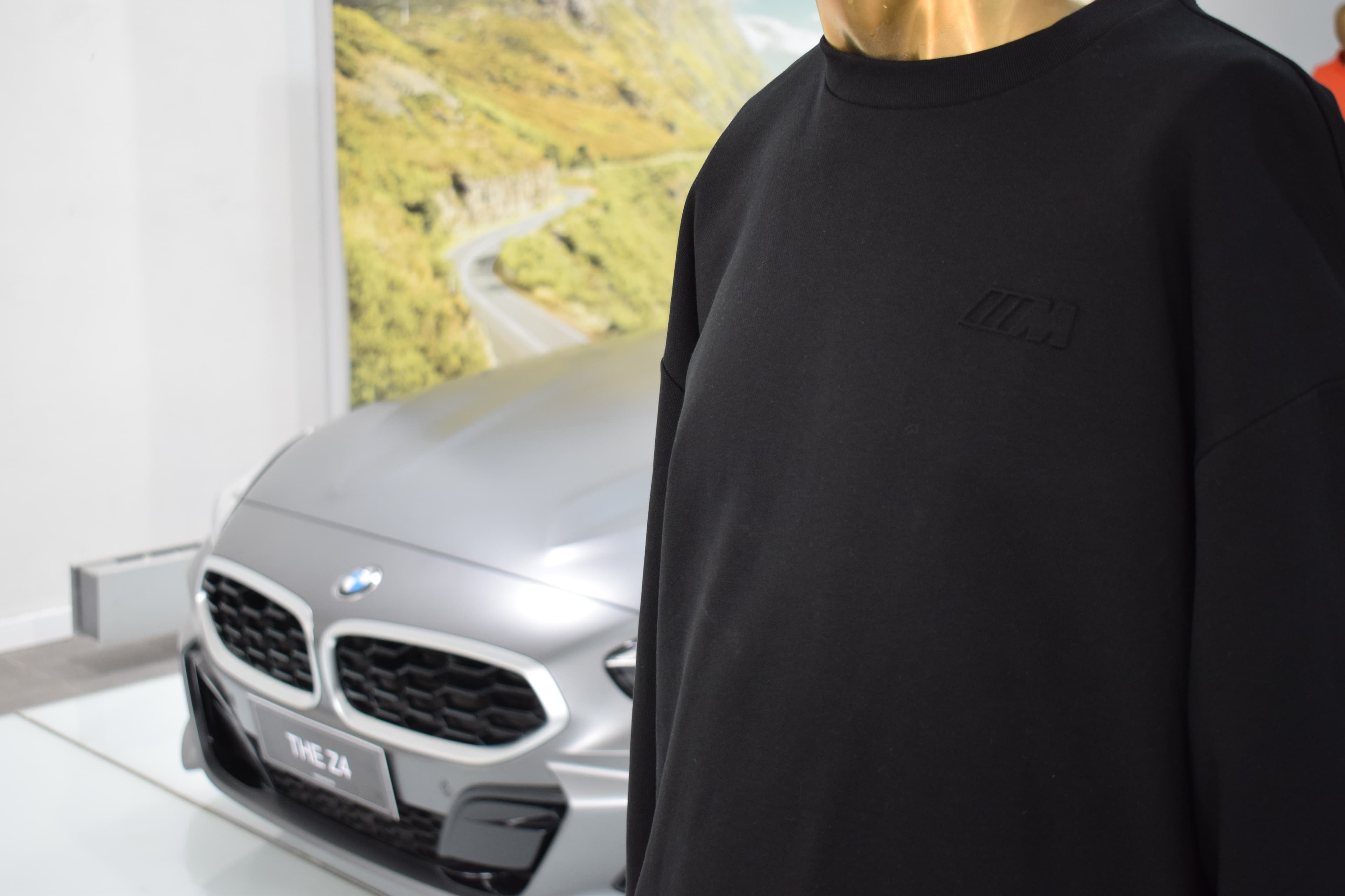 Buzo negro BMW M Collection exhibido junto a un BMW Z4 en el concesionario