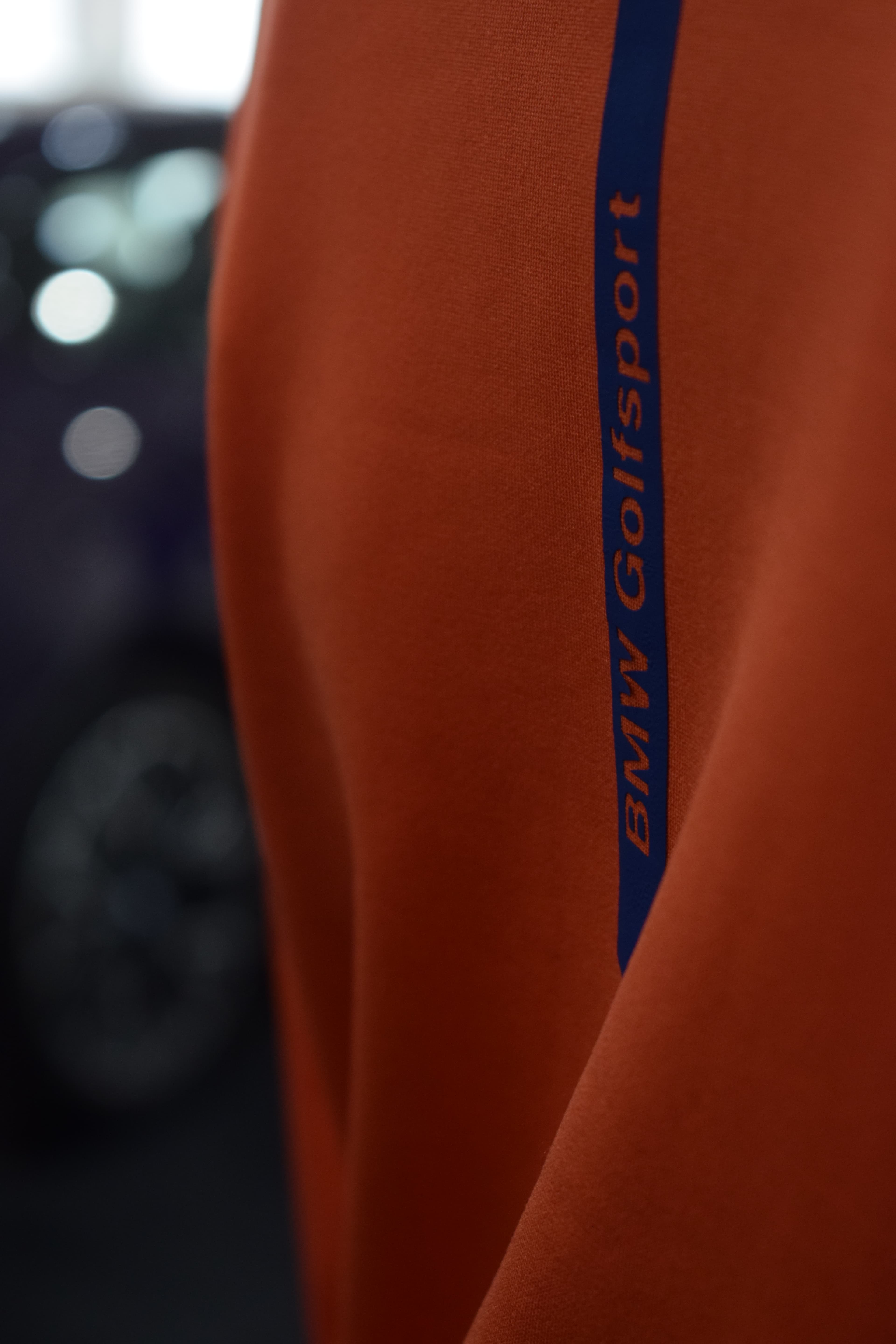 Franja BMW Golfsport en la manga de una campera naranja