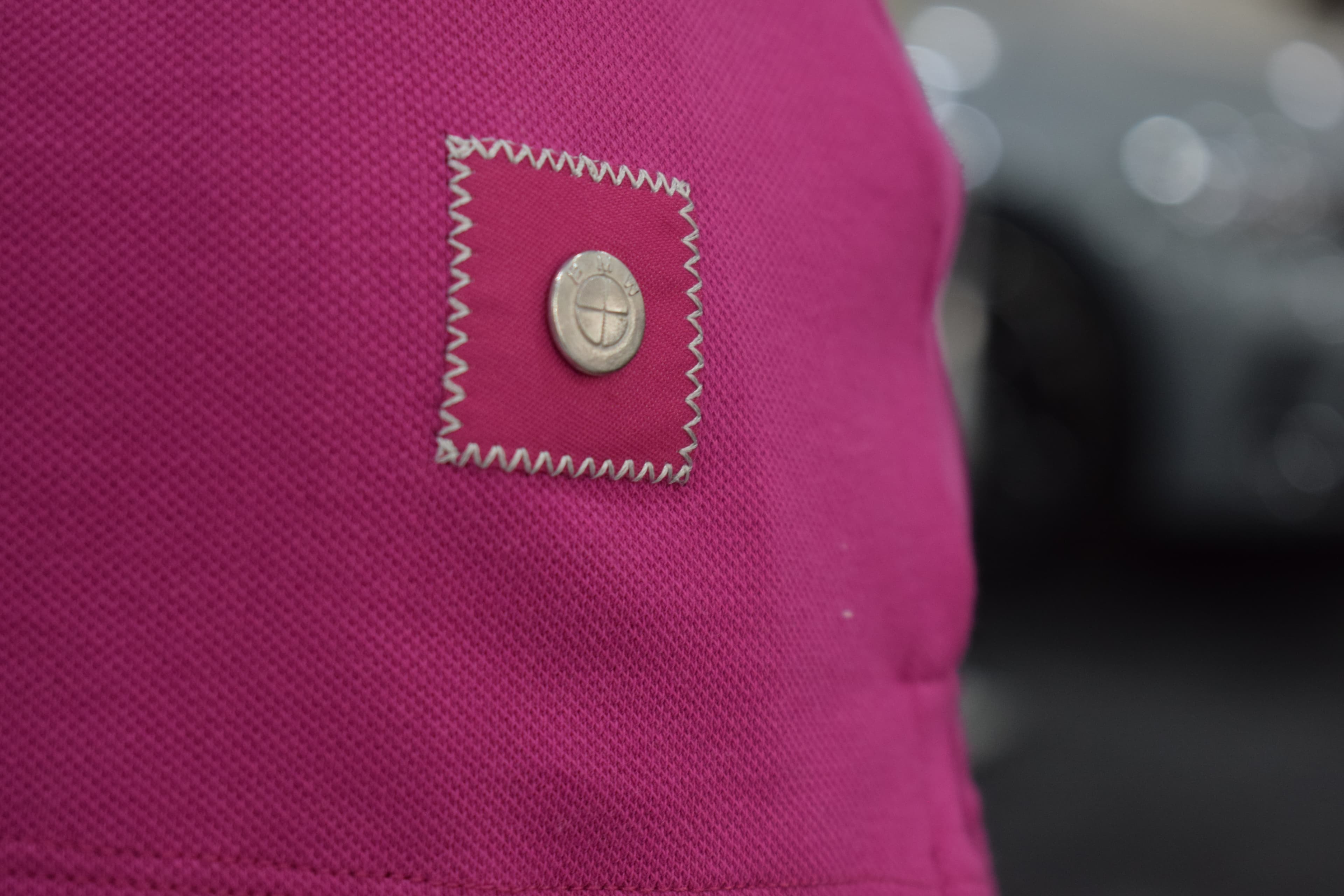 Detalle del botón con logo BMW en una chomba fucsia